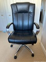 Front view of the black office chair showing padded backrest, seat, armrests, and five-wheel base.
