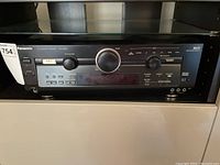Front view of Panasonic SA-HE100 AV Receiver showing power button, volume knob, and input options.