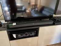 Sony HT-S350 soundbar placed under a TV, showing its front and top controls, next to a black Sony RCD player in a cabinet below.