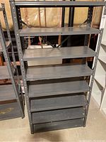 Front view of metal shelving unit showing all 8 shelves and dark finish with some wear.