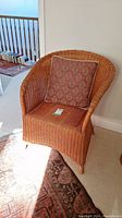 Front view of the wicker chair showing curved design and patterned back cushion.