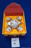 Boxed porcelain tea set with teapot and four teacups, decorated with birds and flowers, within a yellow and red presentation box.