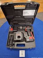 Open carrying case showing cordless Craftsman power drill, battery charger with power cord, rechargeable 14.4 volt battery pack, and instruction manual.