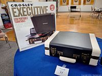 Closed Crosley Executive turntable in suitcase format next to the original box.