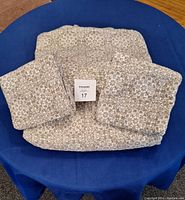 Folded queen sheet set on blue surface, showing fitted sheet, flat sheet, and pillowcases folded neatly.