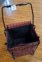 Top-down view of open plaid fabric basket of rolling cart with black interior and padded handles on metal frame
