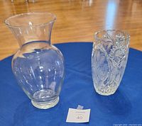 Photo showing both vases: clear glass vase with flared rim and smaller cut crystal vase with etched design