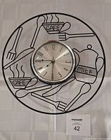 Front view of the cafe kitchen themed wall clock with coffee cups, utensils, and milk jug wireframe design.
