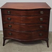 Front view of the 1950s mahogany 4 drawer dresser showing the curved drawer fronts and antique brass oval handles.
