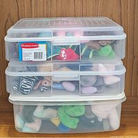 Three clear Rubbermaid plastic storage containers stacked, filled with assorted TY Beanie Babies plush toys showing various animal shapes and colors.