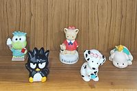 Lot displayed on wooden shelf showing all five character ceramic coin banks in a row
