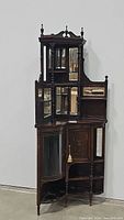 Full frontal view of entire carved wooden corner curio cabinet showing overall form and finish