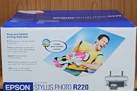 Close-up front side of original Epson Stylus Photo R220 printer box showing branding and product image with person holding photo printout.