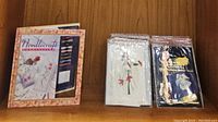 Needlepoint kits displayed in plastic sleeves showing angel and floral designs