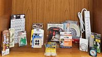 Overview of all utility items arranged on table including power strip, timer, hooks, carpet tape, spray can