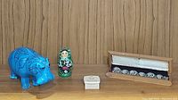 Four main items shown together: blue hippo figurine, nesting doll, Happy Birthday musical box, wooden box with metal bracelet.
