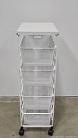 Front view of white mesh cabinet with four pull-out mesh baskets and flat top.