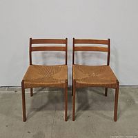 Front view of the pair of mid century wooden chairs with woven rattan seats showing the ladder back design and seat details.