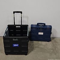 Both collapsible mobile storage crates side by side, black crate extended with handle up and blue crate closed with handle down