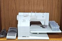 Front-right angle of machine showing extension table, foot pedal, and bobbin case