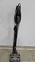 Full upright view of Shark Apex vacuum showing black/gray body and power cord wrapped on side.