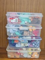 Stack of four clear plastic containers filled with assorted Ty Beanie Babies plush toys. Each container is visible with various animals and characters in different colors.