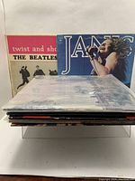 Front view of standing vinyl LP covers featuring Janis Joplin mid-performance and The Beatles "Twist and Shout" album cover.