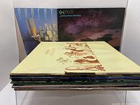 Stack of 11 vinyl LP albums with visible covers from Genesis and Supertramp at back, some damage and wear on covers.