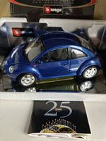 Blue metallic Volkswagen New Beetle die-cast model car inside clear display case with Burago packaging visible behind.