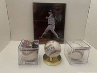 Photo showing all four items in the lot: signed Pat Hentgen picture, Pudge Rodriguez autographed baseball with certificate in display case, Anthony Rizzo autographed baseball in display case, and official MLB baseball on gold stand.