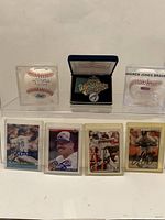 Complete lot showing all items: 1992 Blue Jays World Series pin in case, two baseballs in display cases including one signed by Andrew Jones, and four signed baseball cards in plastic sleeves