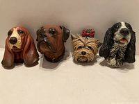 Four dog head wall plaques arranged side by side showing front view of Basset Hound, Boxer, Yorkie, and Spaniel