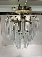 Front and side view of the chandelier ceiling light fixture showing clear acrylic vanes on metal frame.