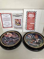 Two Dale Earnhardt NASCAR collector plates in black frames alongside original boxes and certificates of authenticity
