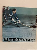 Front cover of the vinyl LP titled "All My Hockey Secrets" showing Frank Mahovolich playing hockey on ice in blue uniform, signed on front in blue ink.