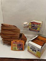 Photo of MacGregor baseball glove, official American League baseball, and Topps 1980s baseball album sticker display box with individual sticker pack in front.