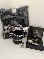 Black NASCAR t-shirt, NASCAR coffee mug, commemorative knife in black box, and keychain arranged together