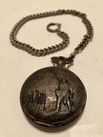 Railroad pocket watch showing engraving of man and railroad tracks, attached to chain
