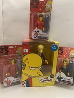 Group photo showing all four collectible figures in their unopened boxes: Mr. Burns, Tony Hawk, Tom Hanks, and Yao Ming.