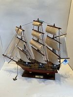Side view of USS Constitution wooden model ship with sails and rigging on wooden base.
