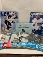 Ten hockey programs arranged showing a mix of color and black and white covers, with one blue Maple Leaf Oldtimers program, a color Toronto Marlies program from 2009-10, and older black and white Maple Leaf Gardens programs featuring players.