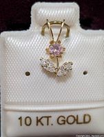Photo of the 10K gold floral pendant with pink and clear cubic zirconia stones on a white display card labeled '10 KT. GOLD'