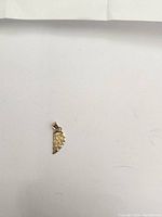 Photo of a small gold pendant with a lattice design on a white background.