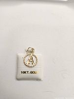 Photo of the 10k gold pendant with letter 'A' on a display card stating '10KT. GOLD'