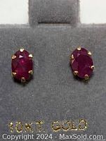 Close-up photo of ruby earrings in gray jewelry display box marked 10KT GOLD.