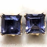 Close-up photo of two square-cut iolite gemstones set in 14K gold with prong settings.