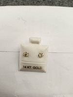 Front view of pair of 14k gold Peridot stud earrings on display card marked '14 KT GOLD'.