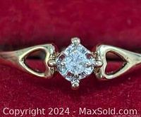 Close-up photo of the gold ring showing open heart accents and central diamond.