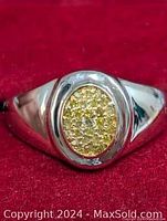 Front view of the ring showing polished silver band and oval cluster of yellow stones with diamond.