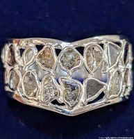 Close-up front view of the silver ring showing diamond-shaped sections with grey diamond fragments embedded in the lattice design.